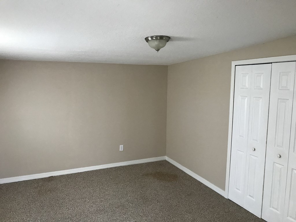 A room with a white door and carpeted floor.