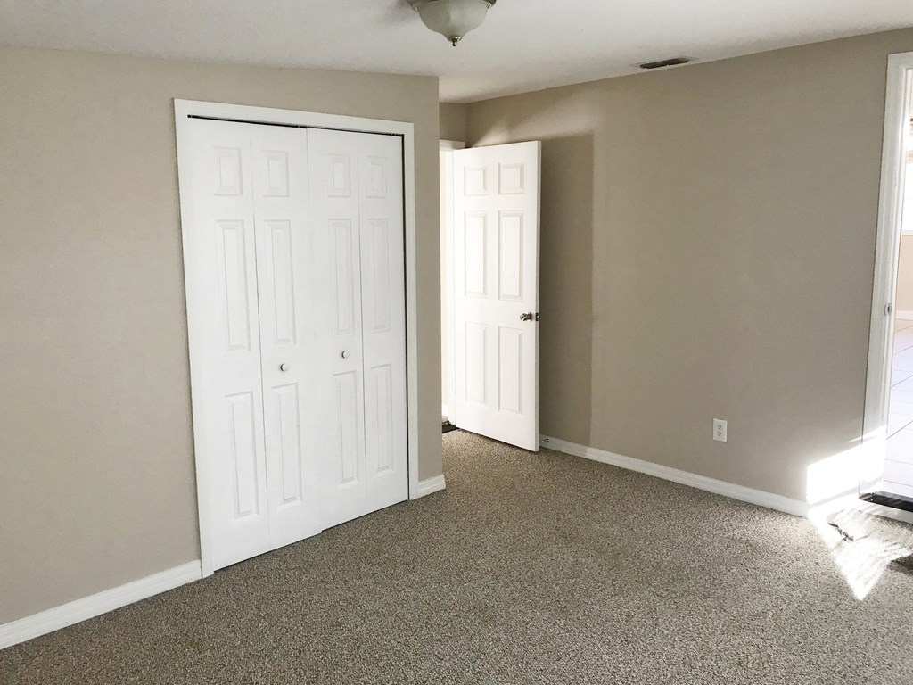 A room with two white doors and carpeted flooring.