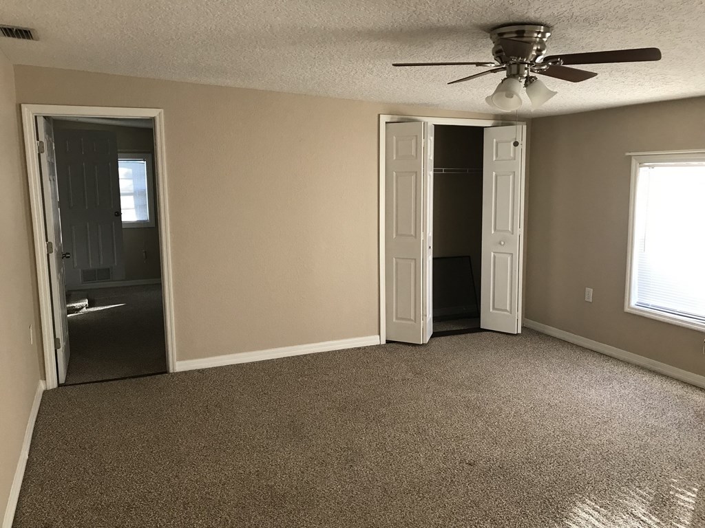 A room with a ceiling fan and carpeted floor.