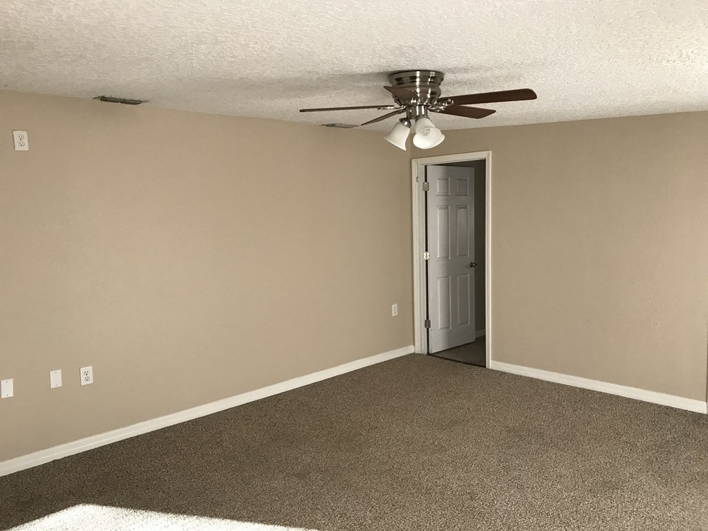 A room with a ceiling fan and a door.