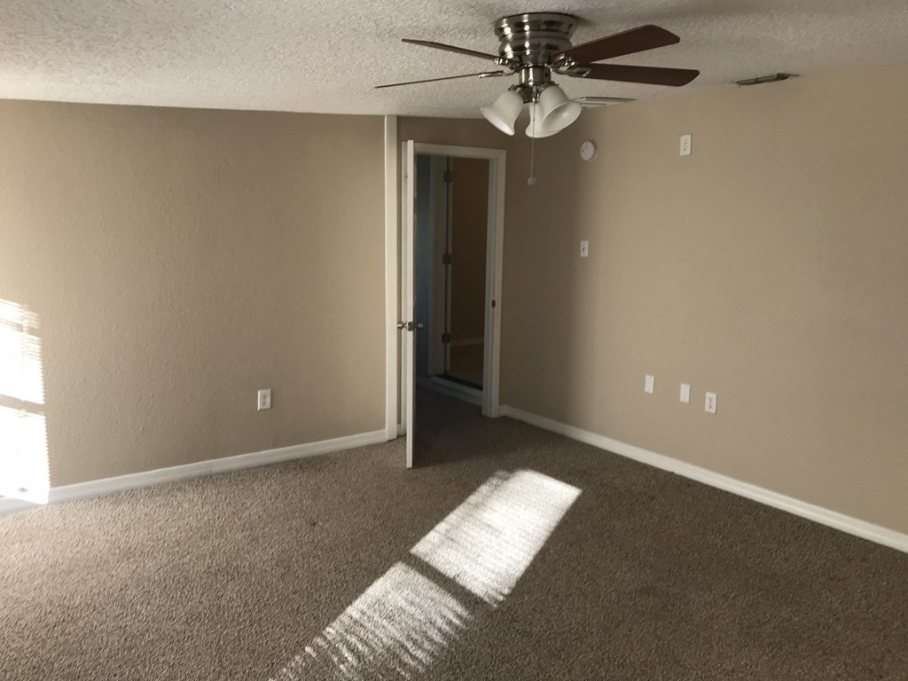 A room with a ceiling fan and a carpeted floor.