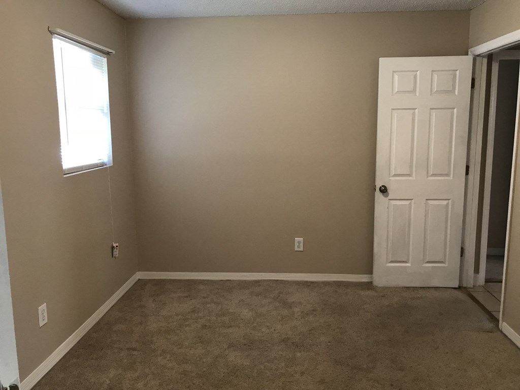 A room with a white door and a window with blinds.