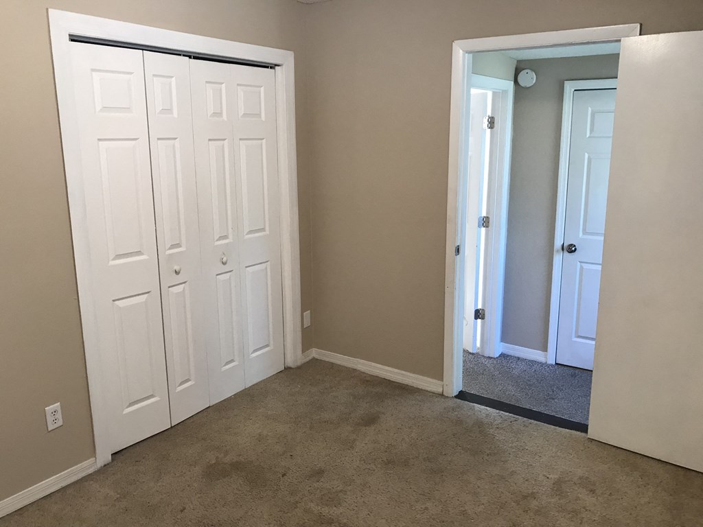 A white door with a black handle is in a room with carpeted floor.