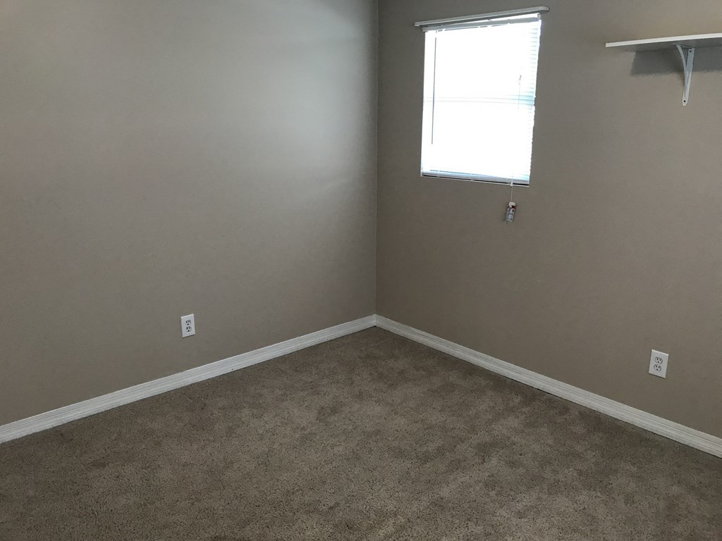 A room with a carpeted floor and a window.