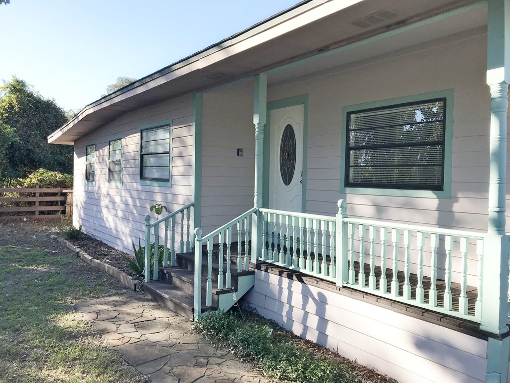 A small house with a green railing and a white door.