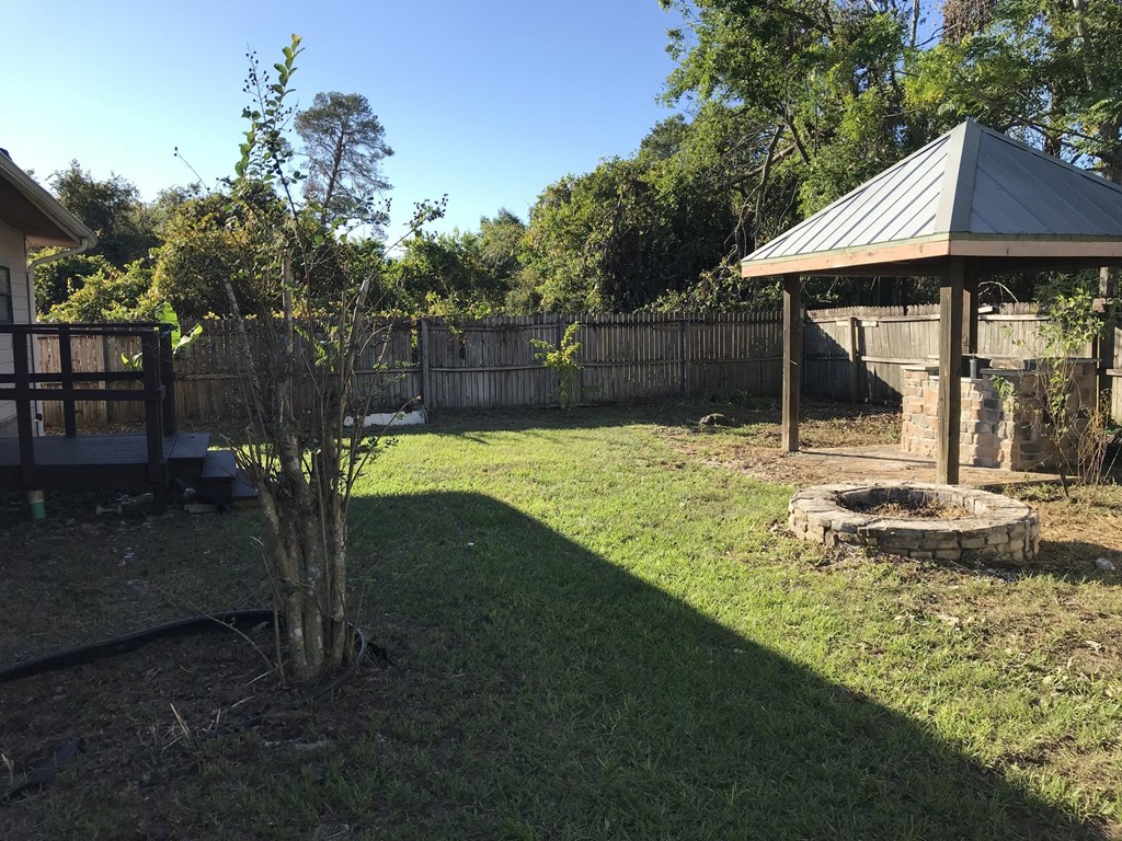 A backyard with a gazebo and a fire pit.