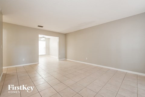 A spacious empty room with tiled flooring and a doorway leading to another room.