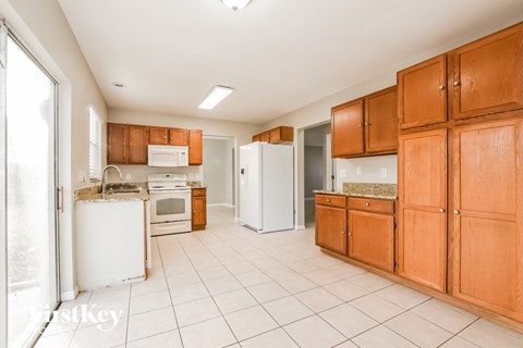 A kitchen with white appliances and wooden cabinets.
