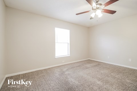 the spacious living room with ceiling fan and carpet