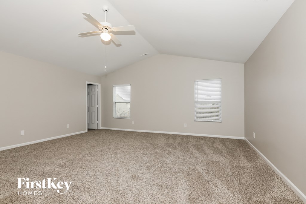 a spacious living room with carpet and a ceiling fan