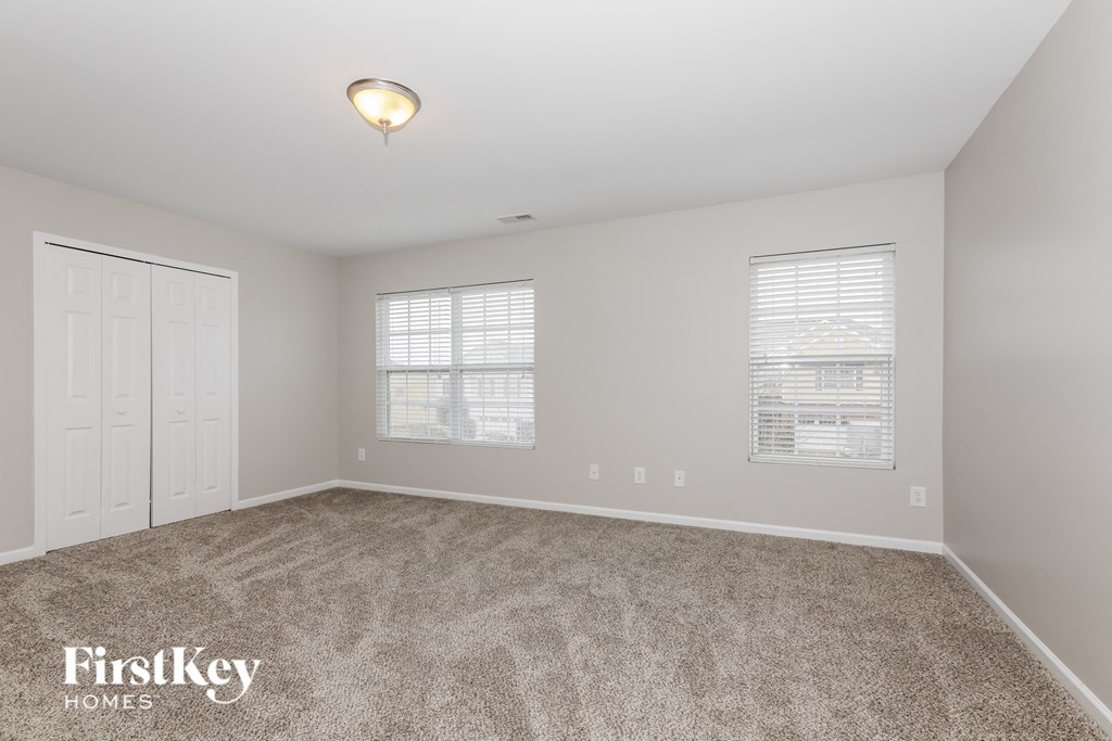a bedroom with carpet and two windows and a door