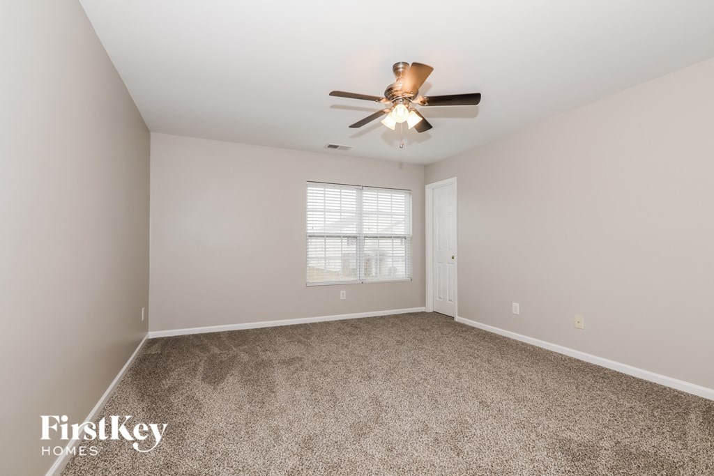 a spacious living room with carpet and a ceiling fan