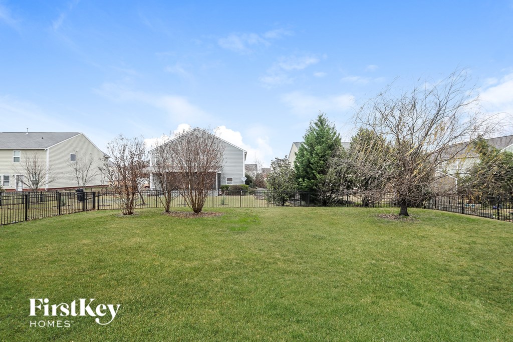a large yard with a fence and houses in the background