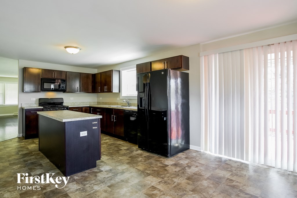 A kitchen with a black fridge and cabinets.