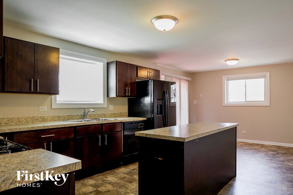 A kitchen with dark wood cabinets and a granite countertop.