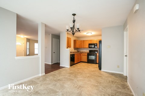 A well-lit, empty living space with a kitchen area in the background.