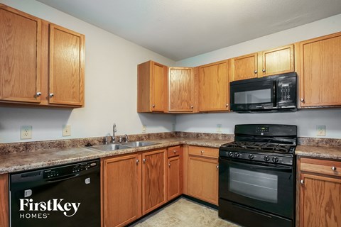 A kitchen with wooden cabinets and a black stove top oven.