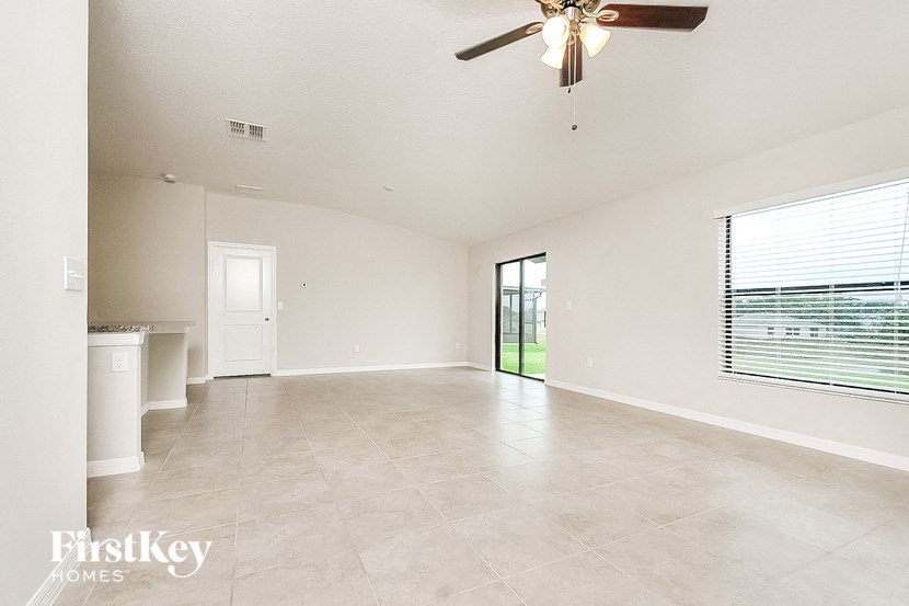 an empty living room with a ceiling fan and a window