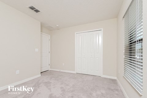 a spacious living room with white walls and a door to a closet