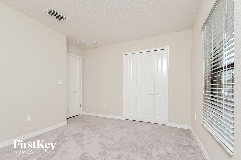a spacious living room with white walls and a door to a closet