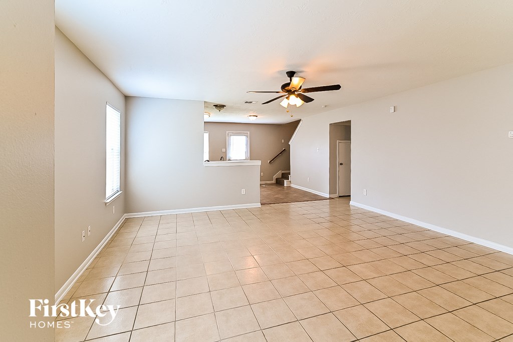 a spacious living room with tile flooring and a ceiling fan