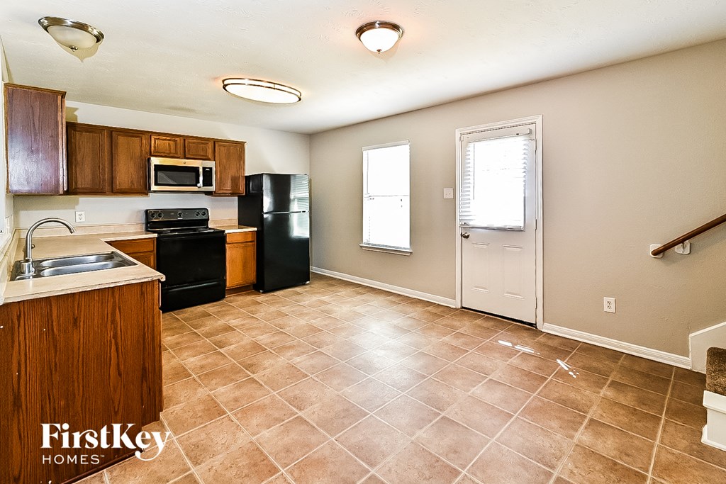 a kitchen with a sink and a black refrigerator