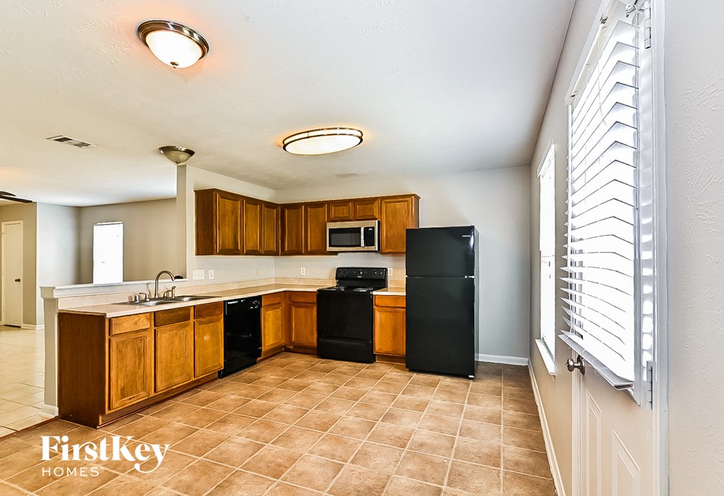 a kitchen with wooden cabinets and a black refrigerator