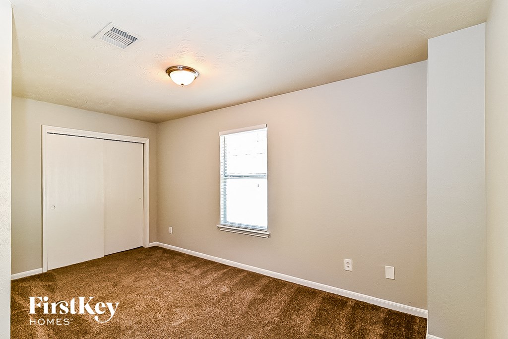 a bedroom with white walls and carpet and a window