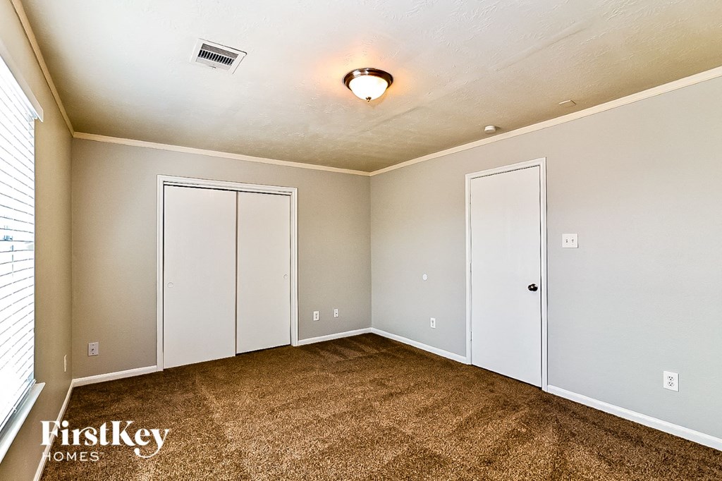 a bedroom with a carpeted floor and two closet doors