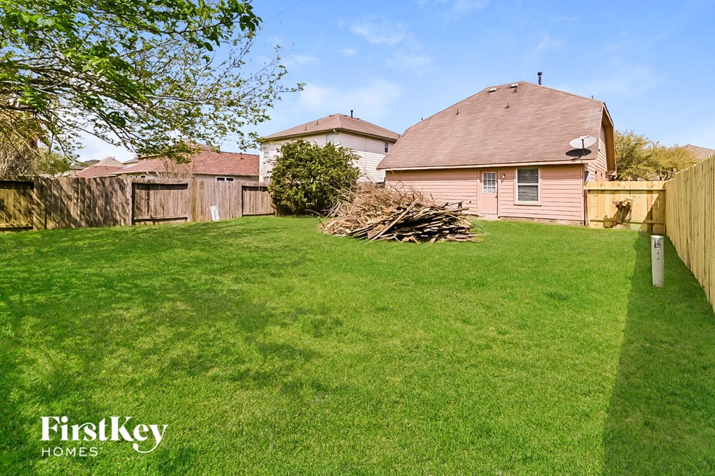 a backyard with a house and a yard with grass and a fence