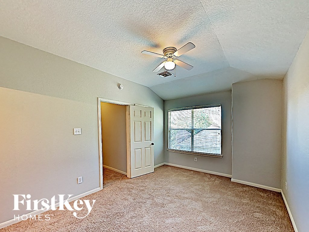 an empty bedroom with a ceiling fan and a window