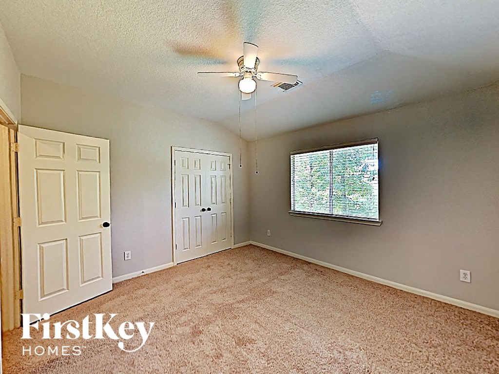 an empty bedroom with a ceiling fan and a window