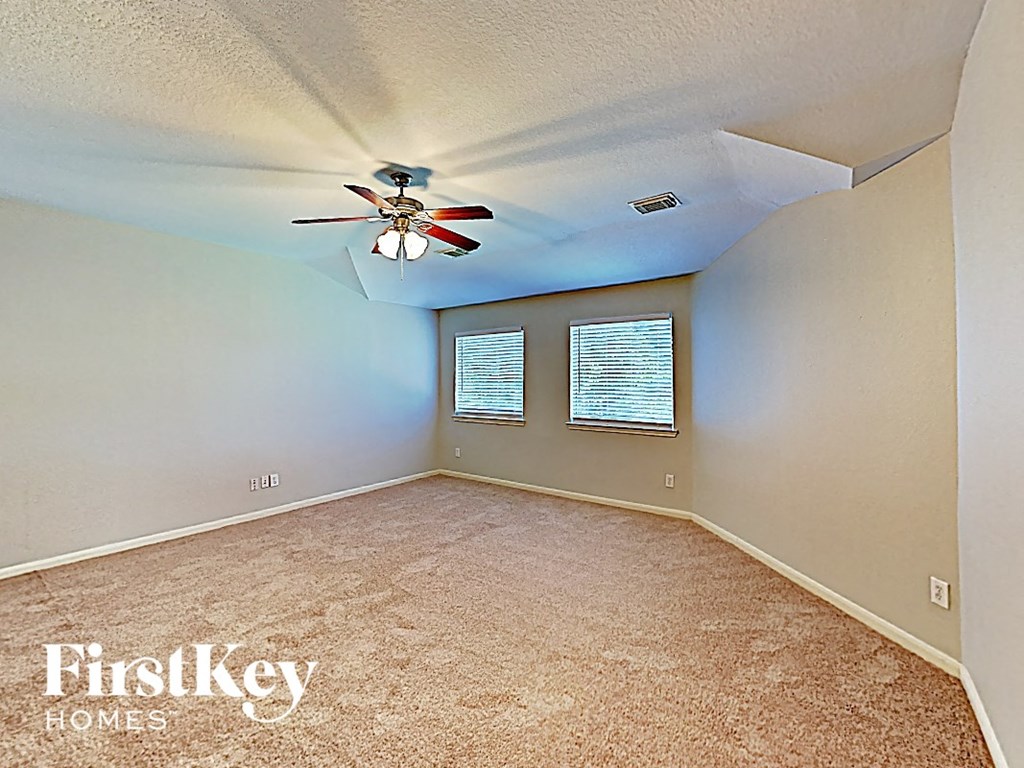 an empty bedroom with a ceiling fan and a window
