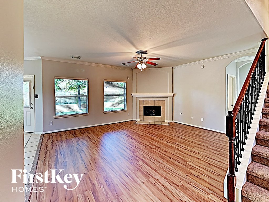 an empty living room with a ceiling fan and a fireplace