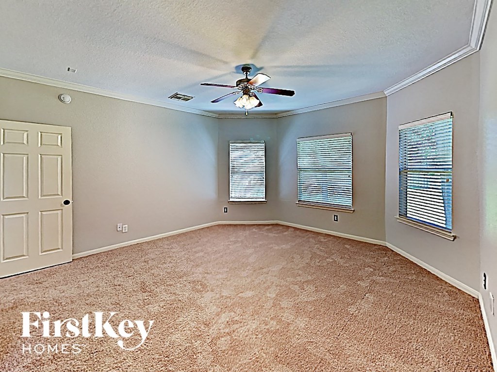 an empty living room with a ceiling fan and a window