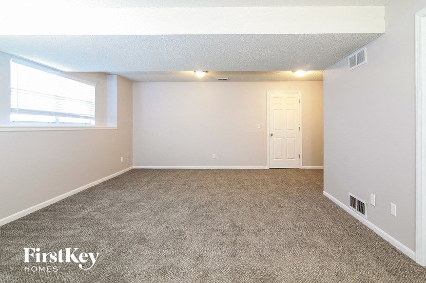 an empty living room with carpet and a window