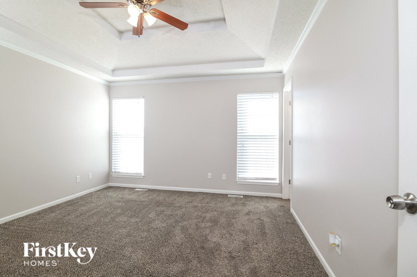 a living room with a ceiling fan and a carpet