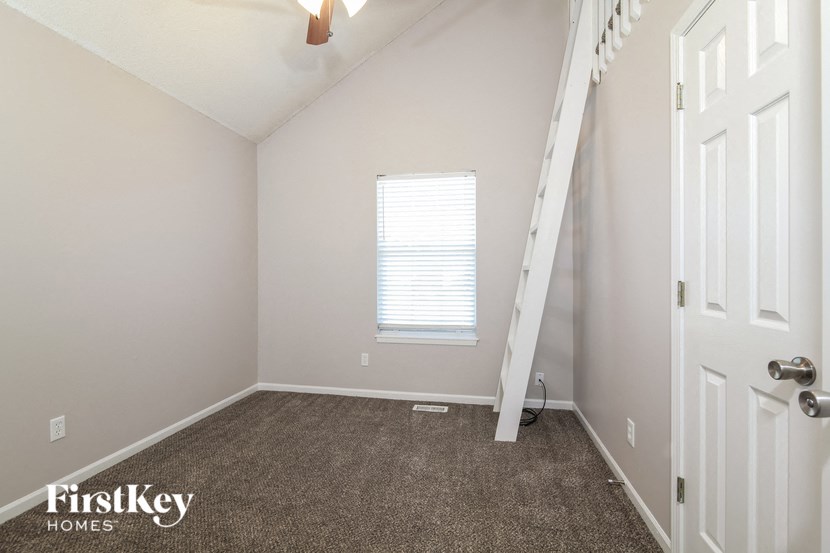 a bedroom with a staircase and a window and a carpeted floor