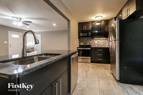 A kitchen with a black fridge and a black counter top.