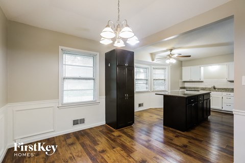 A black refrigerator in a kitchen with wooden floors and white walls.