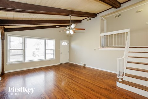 an empty living room with wood floors and a ceiling fan