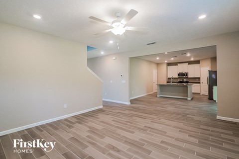 A spacious room with a kitchen area in the background.