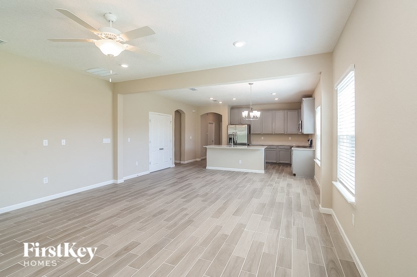 a spacious living room and kitchen with a ceiling fan