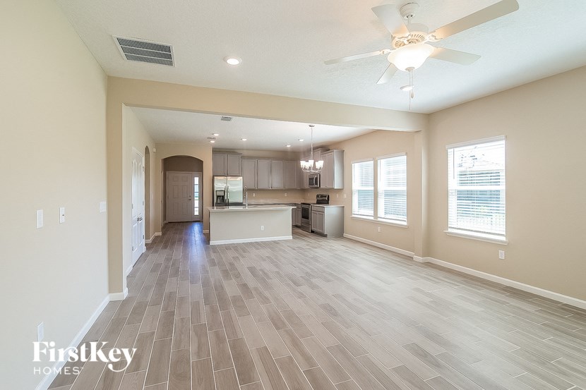 a spacious living room with a kitchen and a ceiling fan