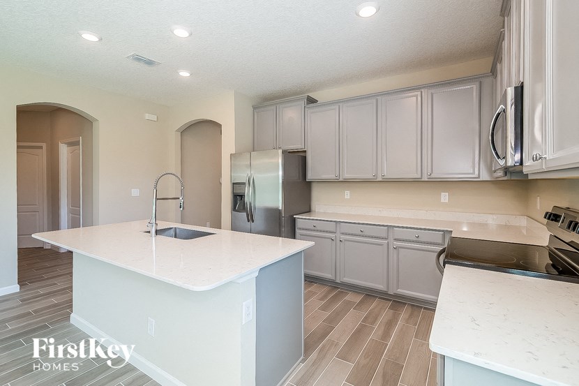 a white kitchen with stainless steel appliances and white counter tops