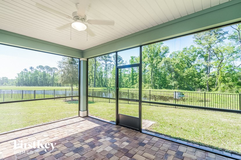 a screened porch with a view of a grass field and trees