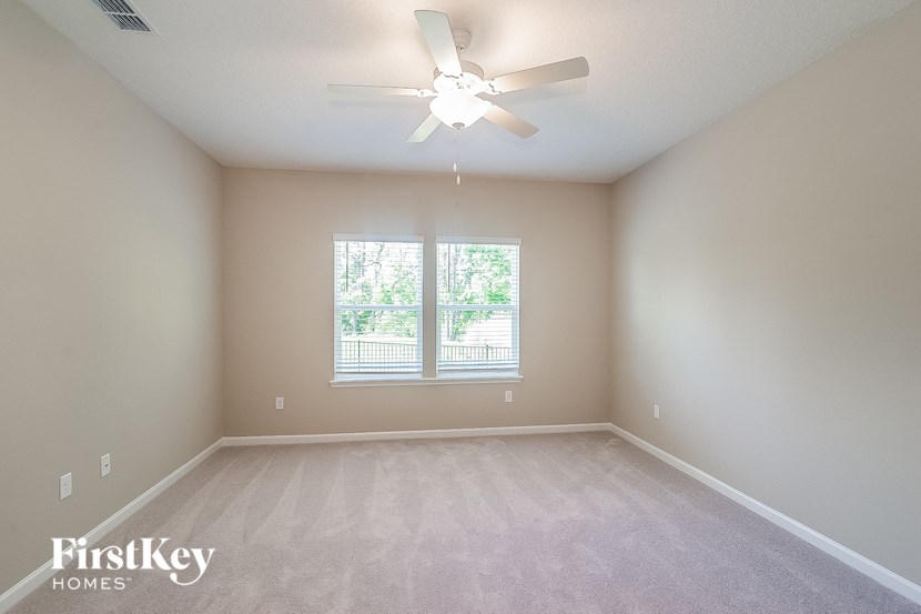 an empty room with a ceiling fan and a window