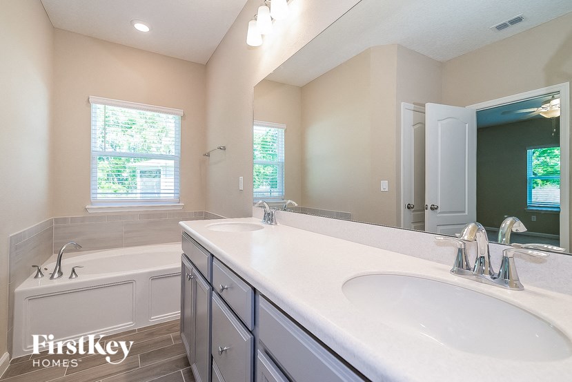 a bathroom with two sinks and a tub and a mirror