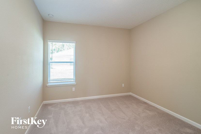 a bedroom with a window and a carpeted floor