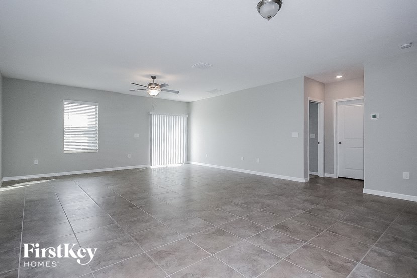 A spacious room with a ceiling fan and a door leading to another room.
